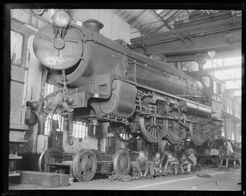 Group of rail workers inspecting and repairing a steam locomotive,- Old Photo